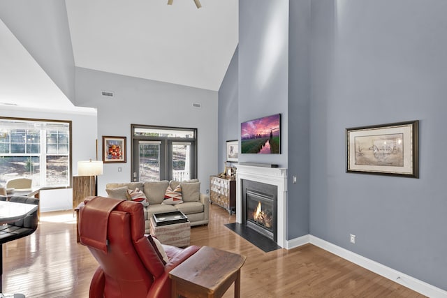 living area featuring wood finished floors, a fireplace with flush hearth, and a healthy amount of sunlight