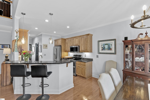 kitchen with a breakfast bar area, light wood-style flooring, a peninsula, appliances with stainless steel finishes, and decorative light fixtures