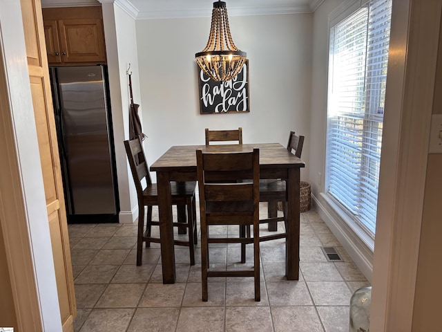 dining space with light tile patterned floors, a notable chandelier, visible vents, baseboards, and crown molding