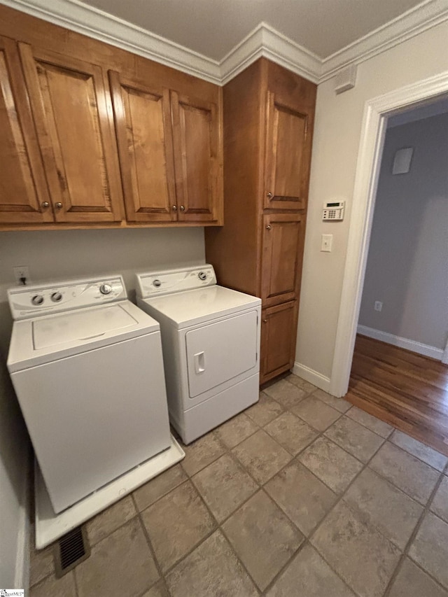 laundry area with cabinet space, baseboards, ornamental molding, and independent washer and dryer