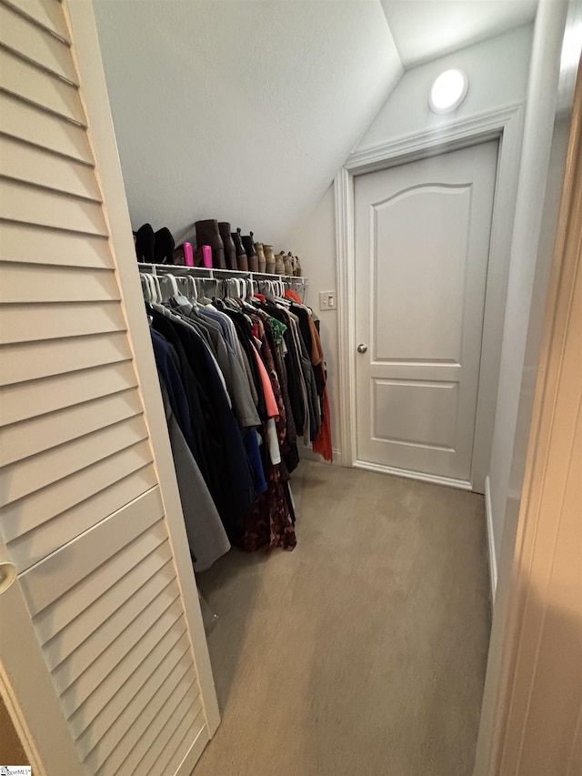 walk in closet featuring carpet floors and vaulted ceiling