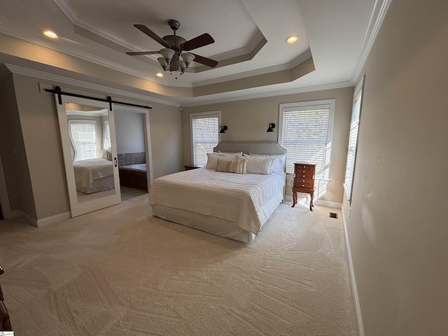 bedroom with light carpet, a barn door, baseboards, a tray ceiling, and crown molding