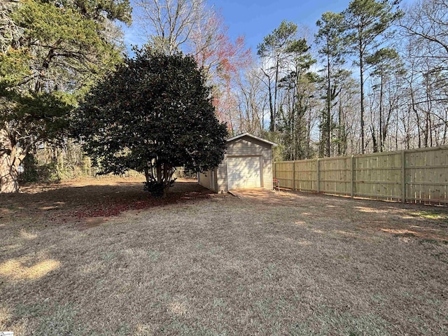 view of yard featuring an outbuilding, driveway, fence, and a garage