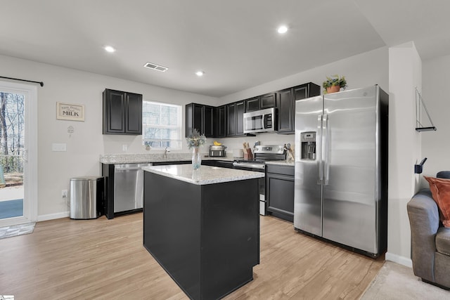 kitchen featuring light stone counters, visible vents, appliances with stainless steel finishes, light wood-type flooring, and dark cabinetry