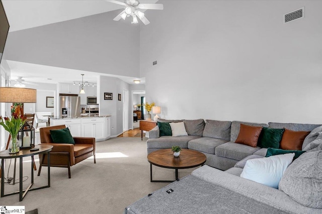 living room featuring light carpet, ceiling fan, a towering ceiling, and visible vents