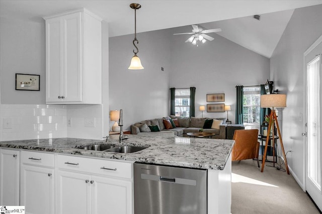 kitchen featuring stainless steel dishwasher, open floor plan, a sink, light stone countertops, and a peninsula