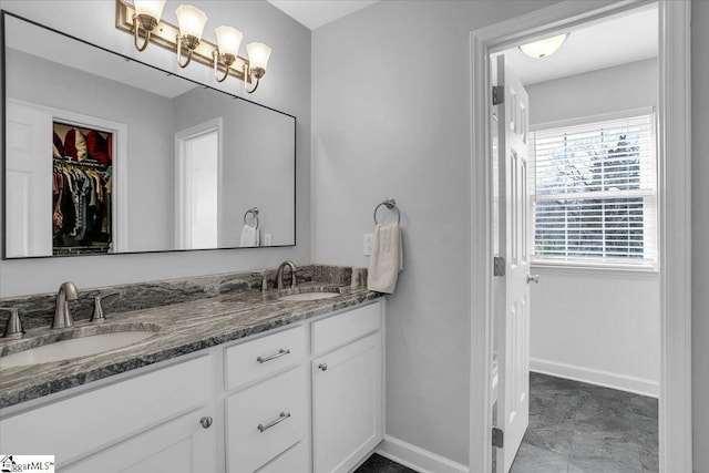 full bathroom featuring a walk in closet, a sink, baseboards, and double vanity