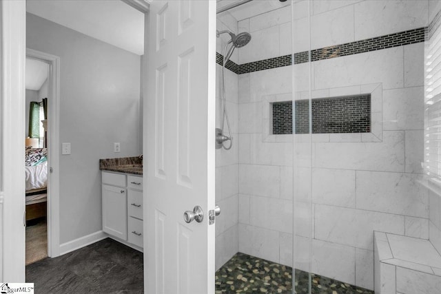 bathroom with a shower stall, vanity, baseboards, and ensuite bathroom