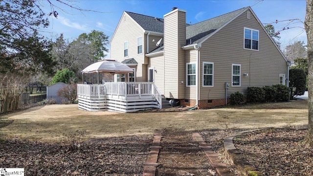 back of property with a deck, a yard, crawl space, and a chimney