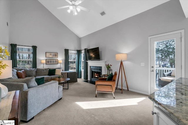 living area with light carpet, a fireplace with flush hearth, visible vents, and a healthy amount of sunlight