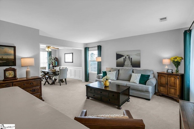 living area featuring a ceiling fan, plenty of natural light, visible vents, and carpet flooring