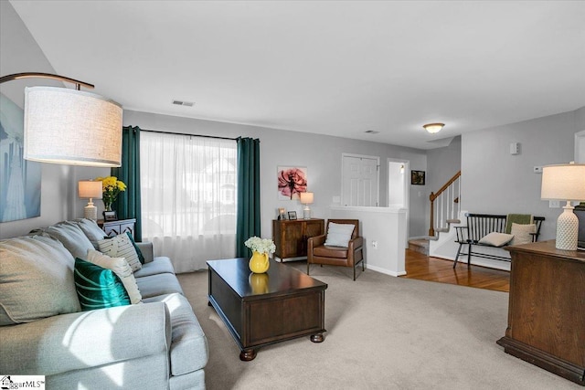 living room featuring carpet floors, visible vents, baseboards, and stairs