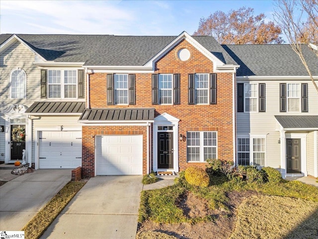 townhome / multi-family property featuring metal roof, a garage, brick siding, driveway, and a standing seam roof