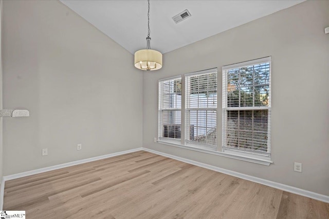 unfurnished room featuring visible vents, vaulted ceiling, baseboards, and wood finished floors