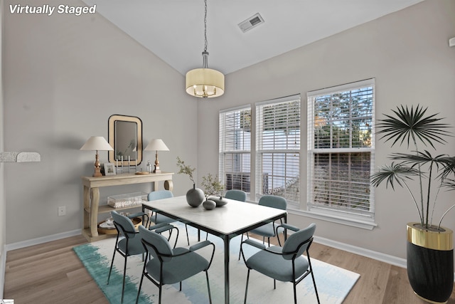 dining room featuring vaulted ceiling, wood finished floors, visible vents, and baseboards