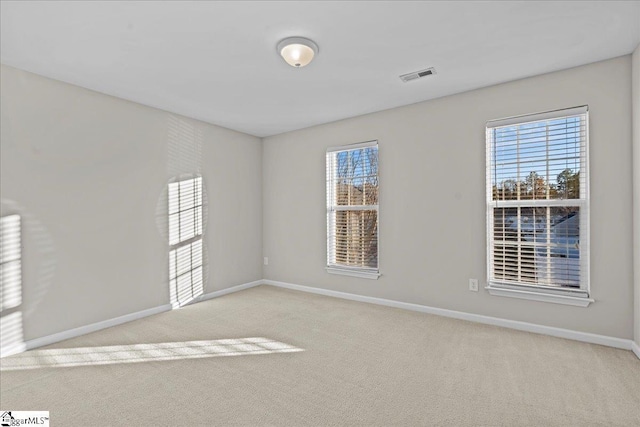 unfurnished room with visible vents, light carpet, and baseboards