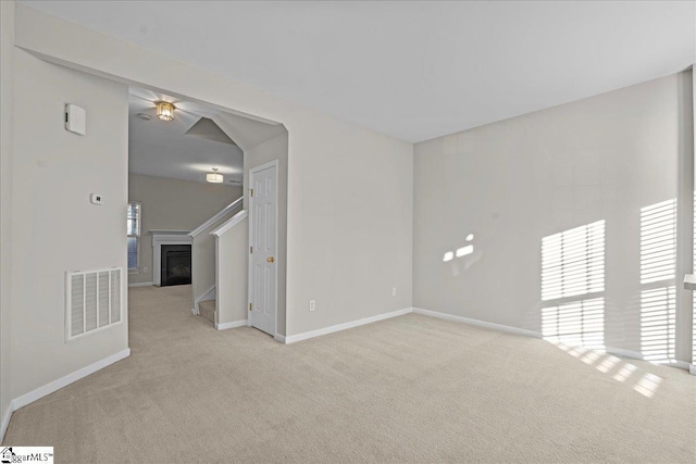 spare room with light carpet, baseboards, a fireplace, and visible vents