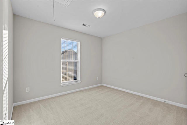 carpeted empty room with attic access, visible vents, and baseboards