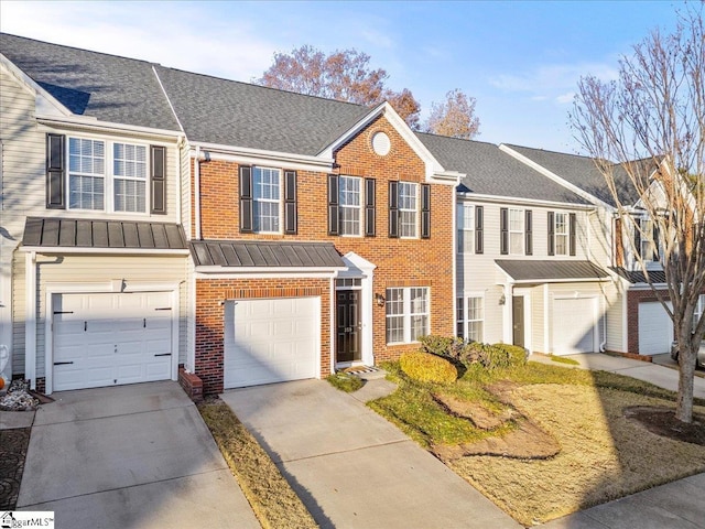 townhome / multi-family property featuring metal roof, an attached garage, brick siding, driveway, and a standing seam roof