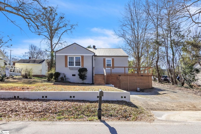 view of front of house with a deck, metal roof, and stucco siding