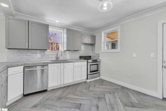 kitchen featuring stainless steel appliances, a sink, baseboards, ornamental molding, and tasteful backsplash