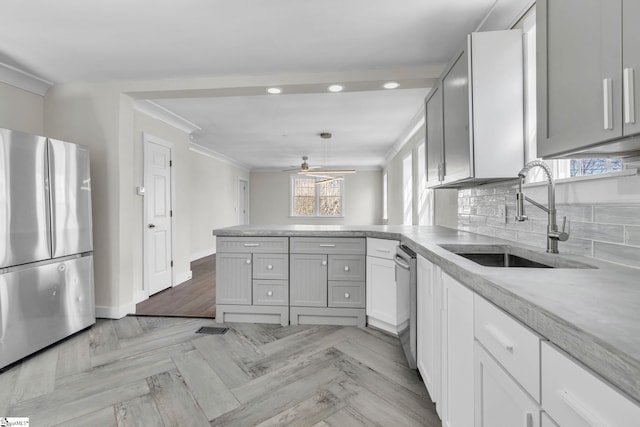 kitchen featuring a peninsula, a sink, ornamental molding, appliances with stainless steel finishes, and backsplash