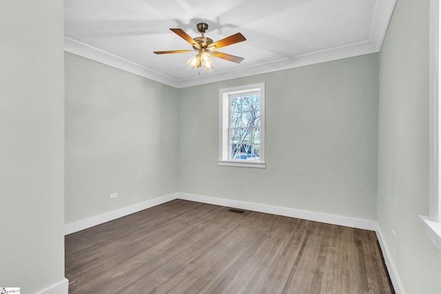 spare room with baseboards, visible vents, ceiling fan, ornamental molding, and wood finished floors