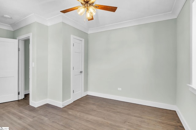 spare room with ceiling fan, baseboards, crown molding, and wood finished floors