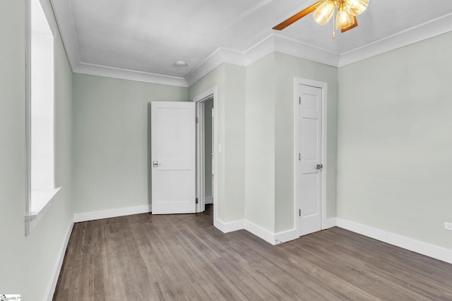 unfurnished bedroom featuring ceiling fan, crown molding, baseboards, and wood finished floors