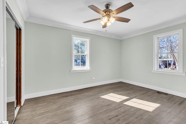 unfurnished bedroom featuring wood finished floors, visible vents, baseboards, a closet, and crown molding