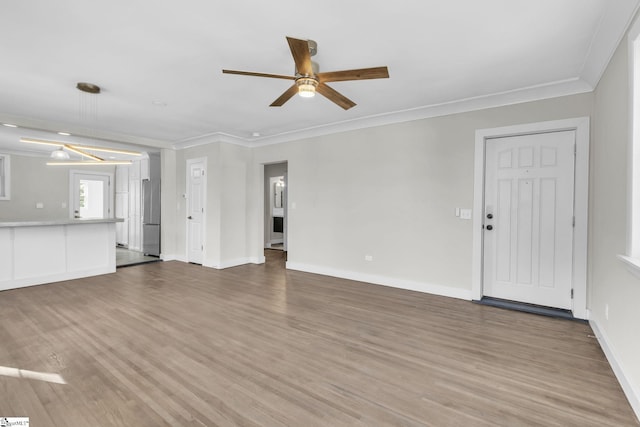 unfurnished living room with ornamental molding, wood finished floors, and baseboards