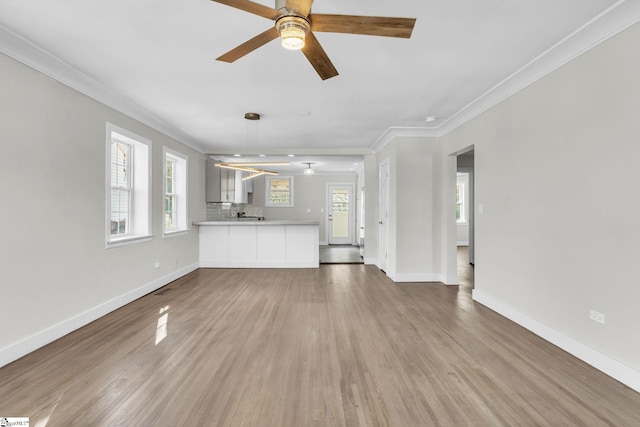 unfurnished living room with ornamental molding, baseboards, and wood finished floors