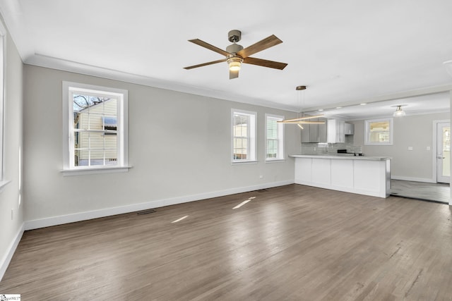 unfurnished living room featuring plenty of natural light, visible vents, crown molding, and wood finished floors