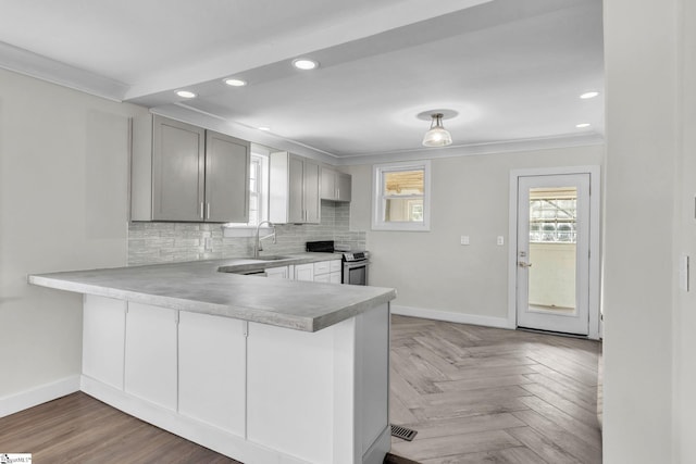 kitchen with a sink, crown molding, backsplash, and stainless steel range with electric cooktop