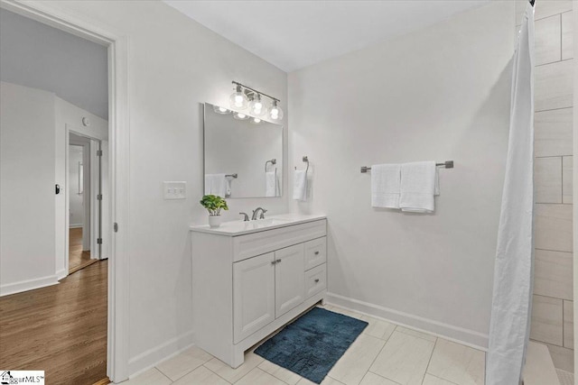 full bathroom with wood finished floors, walk in shower, vanity, and baseboards