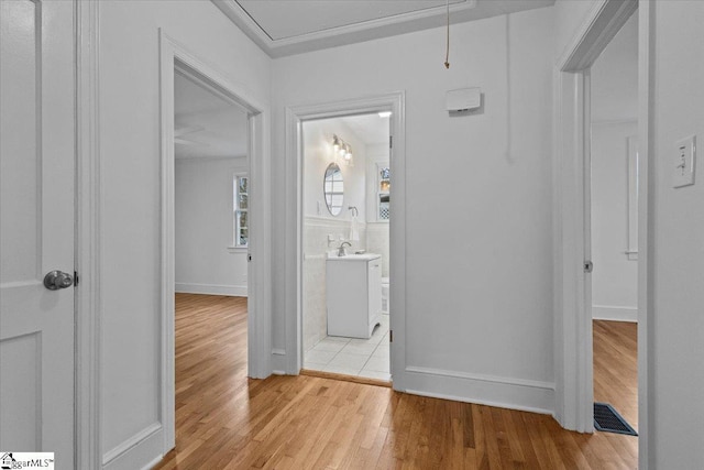 corridor featuring attic access, visible vents, and light wood-style floors