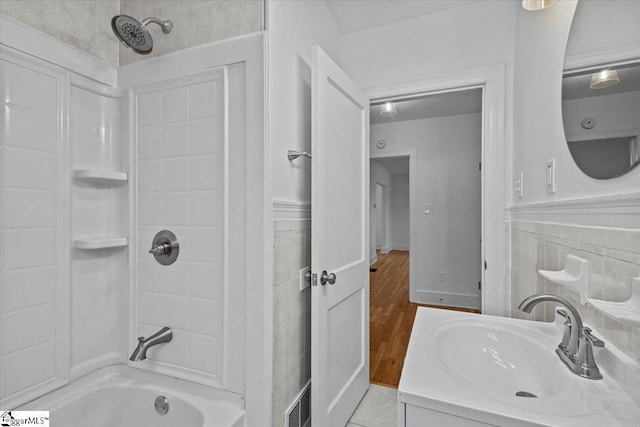 bathroom with bathtub / shower combination, visible vents, a sink, and tile walls