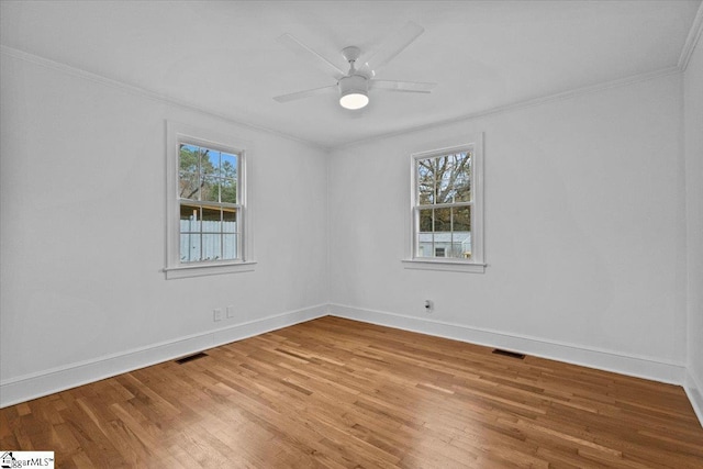 empty room featuring light wood-style floors, visible vents, and ornamental molding