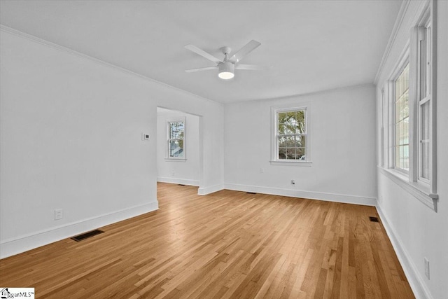 spare room featuring crown molding, a healthy amount of sunlight, visible vents, and light wood-style floors