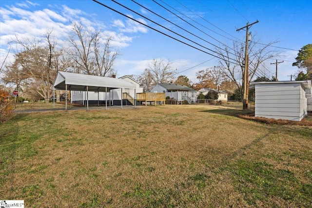 view of yard with a detached carport, fence, and an outbuilding