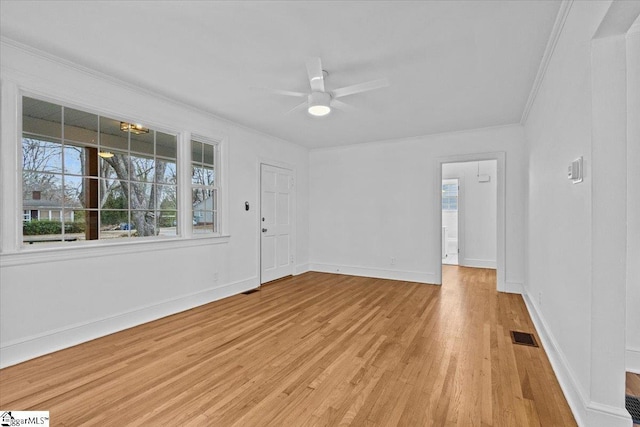 interior space with visible vents, ornamental molding, light wood-style floors, ceiling fan, and baseboards