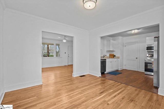 interior space with crown molding, visible vents, light wood-style floors, a sink, and baseboards