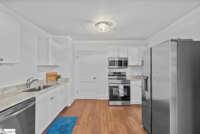 kitchen featuring stainless steel appliances, light wood-style floors, white cabinetry, and a sink