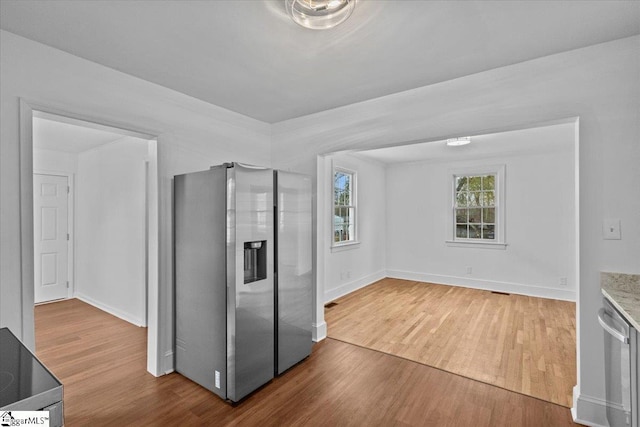 kitchen with stainless steel refrigerator with ice dispenser, baseboards, and wood finished floors