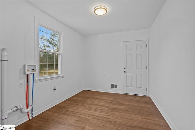 unfurnished room with baseboards, visible vents, and wood finished floors