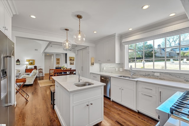 kitchen with decorative backsplash, appliances with stainless steel finishes, open floor plan, and a sink