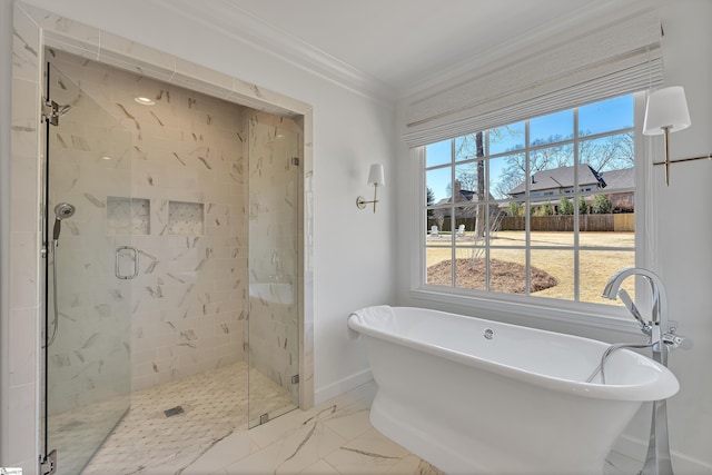 bathroom featuring marble finish floor, ornamental molding, a stall shower, a freestanding tub, and baseboards