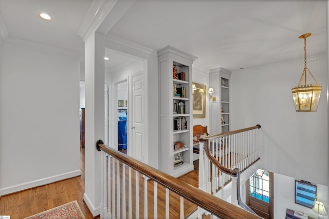 corridor featuring ornamental molding, light wood-type flooring, and an upstairs landing