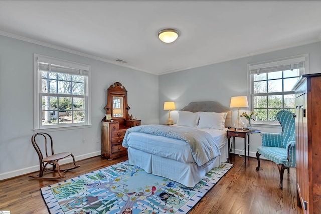 bedroom with baseboards, wood finished floors, visible vents, and crown molding