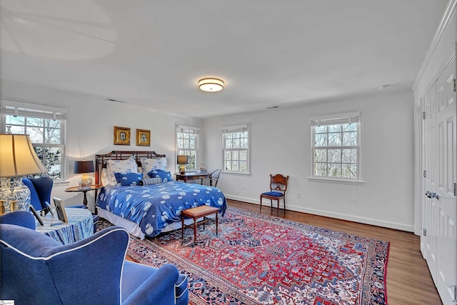 bedroom featuring baseboards, visible vents, and wood finished floors